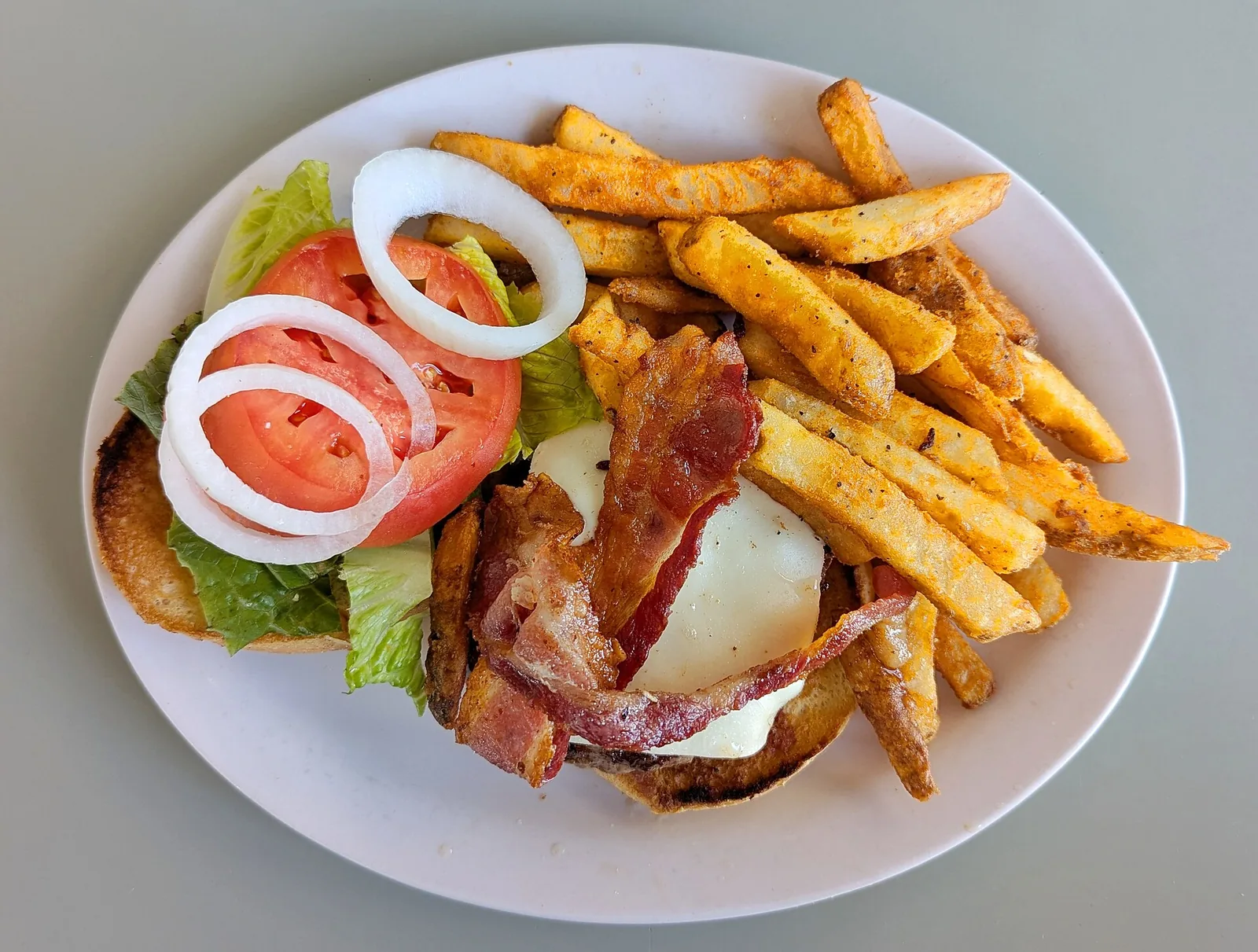 A bacon cheeseburger with fries. The photo was not taken at a Woodstock restaurant.